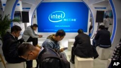 FILE - Attendees look at their smartphones at a booth from chipmaker Intel at the PT Expo in Beijing, China, Oct. 31, 2019.