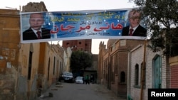 People walk at Al Arafa, known as the city of the dead, near an electoral banner for independent presidential candidate Hany Morgan in old Cairo, March 6, 2013.