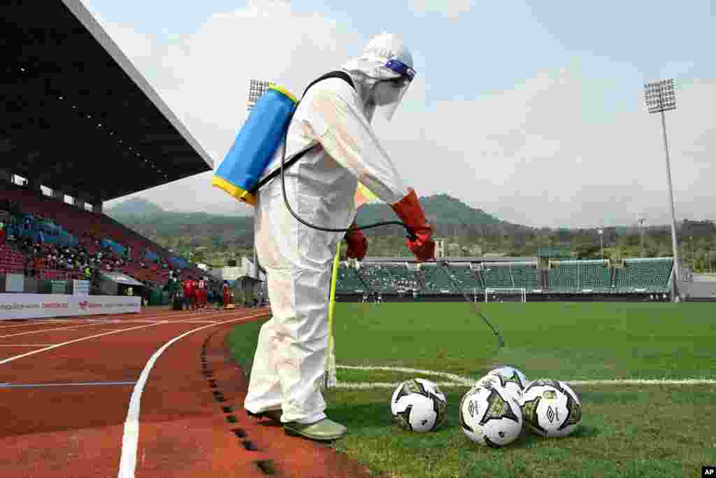 A technician disinfects official balls before the Group F Africa Cup of Nations 2021 football match between Mauritania and Gambia.