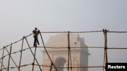 A laborer dismantles scaffoldings near the India Gate war memorial on a smoggy day in New Delhi, February 2013.