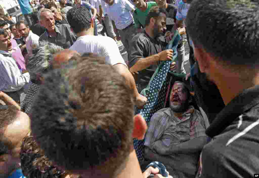 Syrians evacuate a wounded man from under the rubble after an air strike destroyed at least ten houses in Azaz on the outskirts of Aleppo, Syria, August 15, 2012.