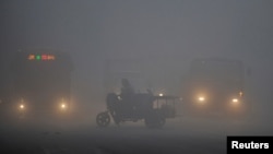 FILE - A tricycle travels past a crossroad on a hazy day in Hefei, Anhui province, March 30, 2014. China is curbing the use of diesel trucks in an effort to tackle air pollution.