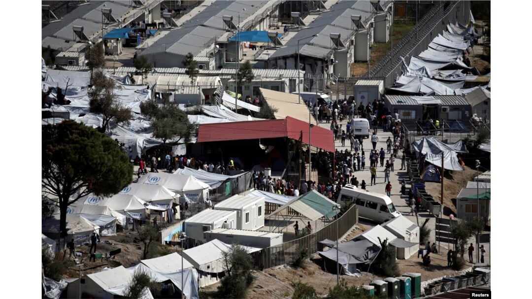 FILE - Refugees and migrants line up for food distribution at the Moria migrant camp on the island of Lesbos, Greece, Oct. 6, 2016.