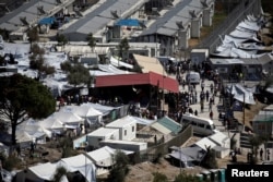 FILE - Refugees and migrants line up for food distribution at the Moria migrant camp on the island of Lesbos, Greece, Oct. 6, 2016.