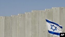 Израелско знаме поставено пред израелската сепаративна бариера во селото Абу Дис на Западниот брег, на периферијата на Ерусалим, среда, 7 јули 2004 година. 