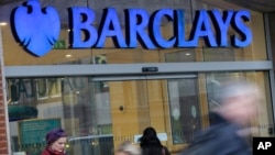 Customers wait outside a retail branch of Barclays Bank to open in London in this February 12, 2013, file photo.