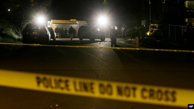 FILE - Crime-scene tape is shown as investigators work under lights at the scene of an overnight shooting.