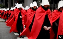 FILE - Women in favor of a measure to expand legal abortions, wearing red cloaks and white bonnets like the characters from the novel-turned-TV series "The Handmaid's Tale", march in silence to Congress, in Buenos Aires, Argentina, July 25, 2018.