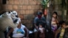 Pekerja kesehatan Ari Nascimento tengah melakukan uji Covid-19 Geralda da Costa. Para kerabat tengah menunggu giliran mereka untuk diuji di Manacapuru, negara bagian Amazonas, Brasil, Rabu, 3 Juni 2020. (Foto: AP/Felipe Dana)