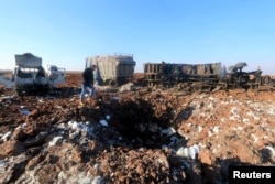 FILE - A man inspects a hole in the ground near damaged trucks at a site hit by what activists said were airstrikes carried out by the Russian air force in Karf Naseh town, Aleppo countryside, Syria, Dec. 26, 2015.