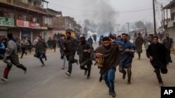 FILE - Kashmiri villagers run for cover from tear gas shells and pellets fired at by Indian police during a protest near the funeral of Rayees Ahmad Dar, a suspected militant of Lashkar-e-Taiba in Kakpora village south of Srinagar, Indian controlled Kashmir.