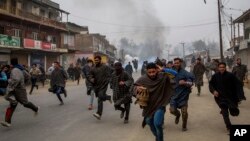 FILE - Kashmiri villagers run for cover from tear gas shells and pellets fired at by Indian police during a protest near the funeral of Rayees Ahmad Dar, a suspected militant of Lashkar-e-Taiba in Kakpora village south of Srinagar, Indian controlled Kashm