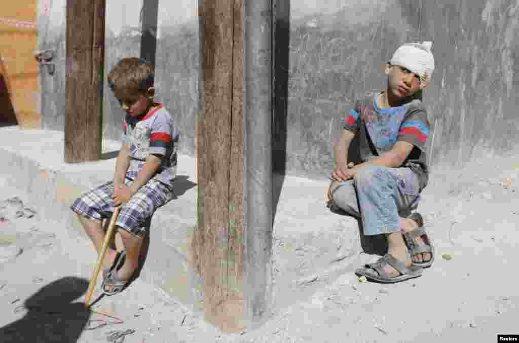 An injured boy sits next to another boy near a site hit by what activists said was a barrel bomb dropped by forces in support of Syria&#39;s President Bashar al-Assad in Sheikh Khodr area in Aleppo. 