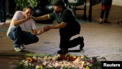 A man comforts Joseph Culver, left, of Charlottesville as he kneels at a late night vigil to pay his respect for a friend injured in a car attack on counterprotesters after the "Unite the Right" rally organized by white nationalists in Charlottesville, Virginia, Aug. 12, 2017.