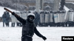 A pro-European protester gestures, with riot police officers seen in the background, during a rally in Kyiv, Jan. 22, 2014.