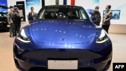 2021年1月5號北京車展上的特斯拉展廳，人們正在觀看一輛藍色特斯拉Y型電動轎車。
