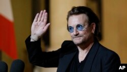 FILE - In this Monday, Sept. 10, 2018 file photo, U2 singer Bono waves good-bye to the media after a meeting with French President Emmanuel Macron at the Elysee Palace in Paris, France. Trump has sought to slash hundreds of millions from U.S. funding for AIDS programs, but Bono tells The Associated Press that members of Congress, “right and left,” have so far turned him down.