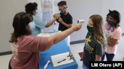 Amid concerns of the spread of COVID-19, science teachers Ann Darby, left, and Rosa Herrera check-in students before a summer STEM camp at Wylie High School Tuesday, July 14, 2020, in Wylie, Texas. (AP Photo/LM Otero)