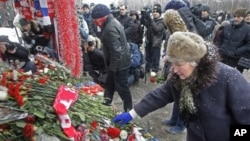People lay flower tributes at a bus stop in Moscow to commemorate Yegor Sviridov, a soccer fan of the Russian club Spartak who was killed in an attack on soccer supporters 40-days ago, during a rally at a bus stop in Moscow, Russia, 15 Jan 2011