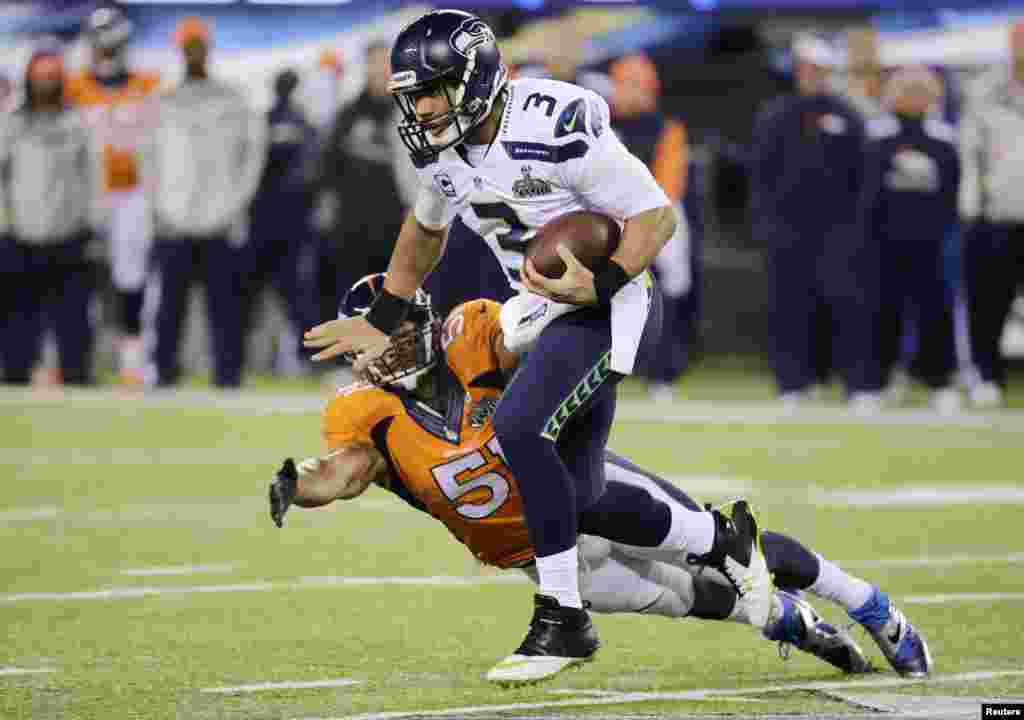Seattle Seahawks quarterback Russell Wilson (3) breaks a tackle by Denver Broncos middle linebacker Paris Lenon during the third quarter in the NFL Super Bowl XLVIII football game in East Rutherford, New Jersey, Feb. 2, 2014.