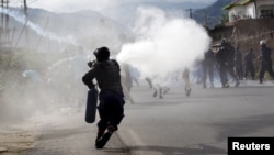 A riot police officer sprays teargas on residents participating in street protests against the decision made by Burundi's ruling party to allow President Pierre Nkurunziza to run for a third five-year term, in the capital Bujumbura, April 26, 2015. 