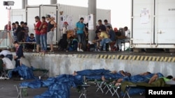 Migrants, who have been picked up within Austria near the border with Hungary, wait at a makeshift camp in Nickelsdorf, Austria, Aug. 29, 2015.