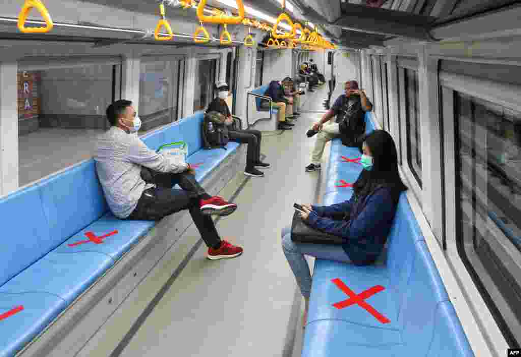 People sit on areas created by red cross marks to ensure social distancing inside a rapid transit train in Palembang, South Sumatra, Indonesia.