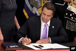 FILE - New York Gov. Andrew Cuomo signs a law that will gradually raise New York's minimum wage, April 4, 2016. New York joins 18 other states by raising its minimum wage in 2017.