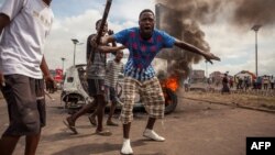 Demonstrators gather in front of a burning car during an opposition rally in Kinshasa, DRC, Sept. 19, 2016.