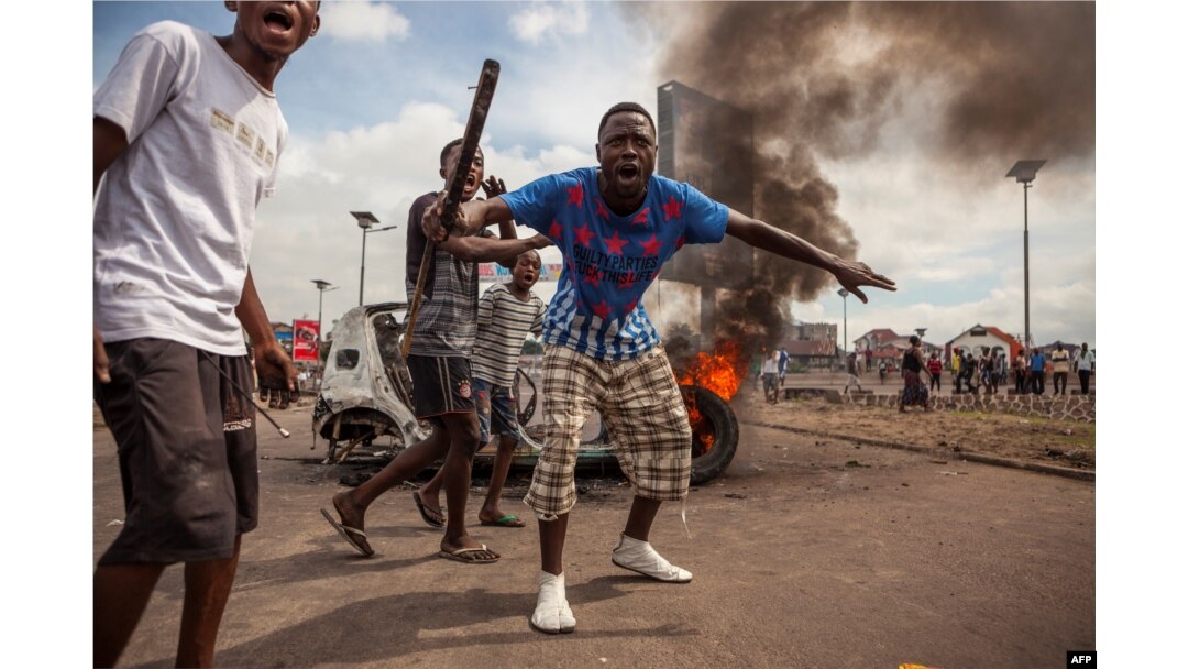 FILE - Demonstrators gather in front of a burning car during an opposition rally in Kinshasa, DRC, Sept. 19, 2016.