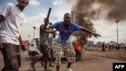 Demonstrators gather in front of a burning car during an opposition rally in Kinshasa, DRC, Sept. 19, 2016.