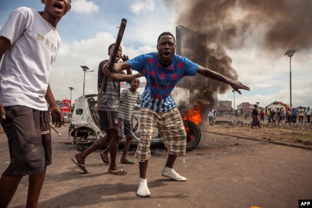 FILE - Demonstrators gather in front of a burning car during an opposition rally in Kinshasa, DRC, Sept. 19, 2016.