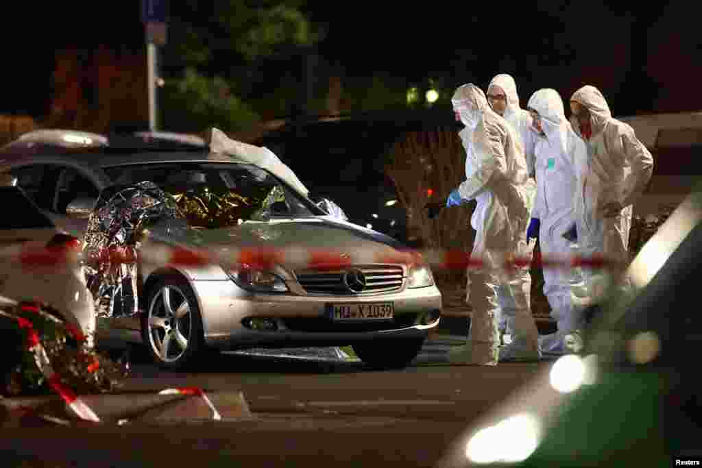 Forensic experts work around a damaged car after a shooting that killed eight people in Hanau near Frankfurt, Germany.