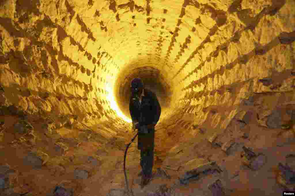 An Iraqi worker operates a drill during a cleanup of the furnace pipes at a cement plant in Najaf, south of Baghdad, April 2, 2014.