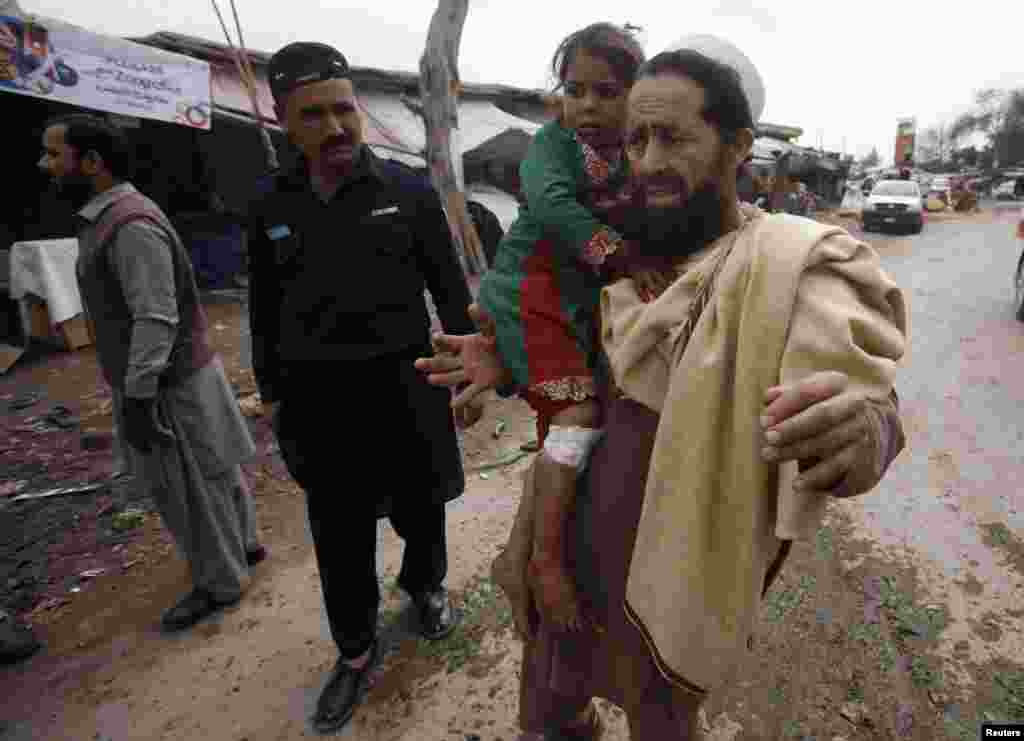 A resident carries his daughter who was injured in a bomb blast on the outskirts of Peshawar, Pakistan, March 14, 2014.