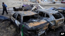 A police officer inspects the aftermath of a car bomb attack at a used car dealer's parking lot in Habibiya, Baghdad, Iraq, April 16, 2013.