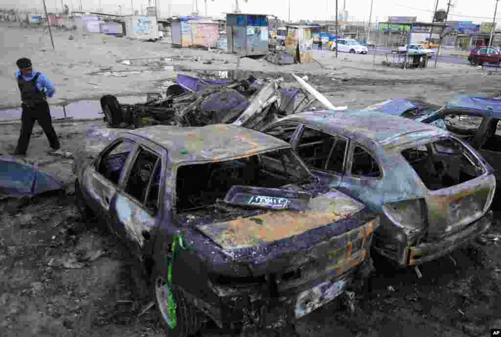 A police officer inspects the aftermath of a car bomb attack at a used car dealer's parking lot in Habibiya, Baghdad, Iraq, April 16, 2013.