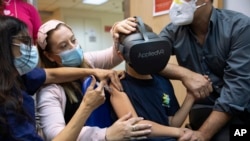 Israeli child Rafael Peled, 8, looks through a VR virtual reality goggles as he receives a Pfizer-BioNTech COVID-19 vaccine from medical staff at the Sheba Tel Hashomer Hospital in Ramat Gan, Israel, Monday, Nov. 22, 2021.