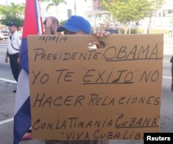 FILE - A protester holds up a sign asking President Obama not to renew relations with Cuba during a rally in solidarity with Cuban dissidents in downtown Miami, Florida.