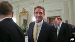 FILE - Sen. Jeff Flake, R-Ariz., center, walks to his seat as he attends a luncheon with other GOP senators and President Donald Trump, July 19, 2017, in the State Dinning Room of the White House in Washington.