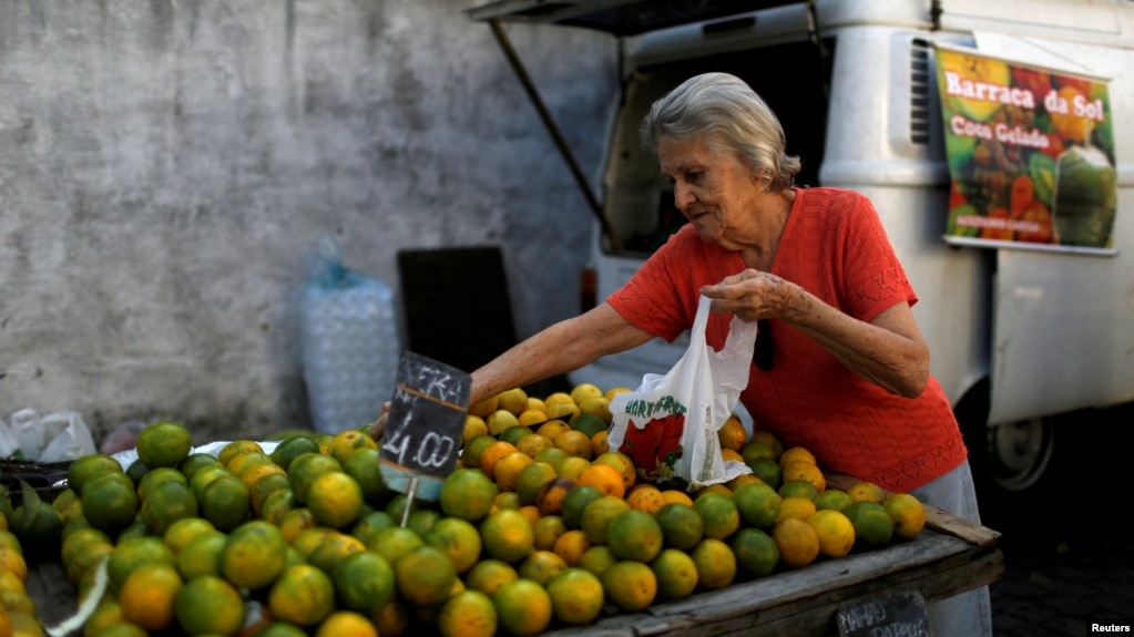 FILE - A customer selects oranges at a street market in Rio de Janeiro, Brazil, May 6, 2016. In an attempt to gain extra revenue, Brazil is poised to offer amnesty to Brazilians who return assets they hold abroad.
