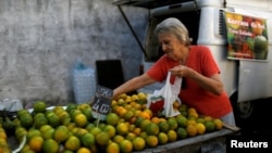 FILE - A customer selects oranges at a street market in Rio de Janeiro, Brazil, May 6, 2016. In an attempt to gain extra revenue, Brazil is poised to offer amnesty to Brazilians who return assets they hold abroad. 