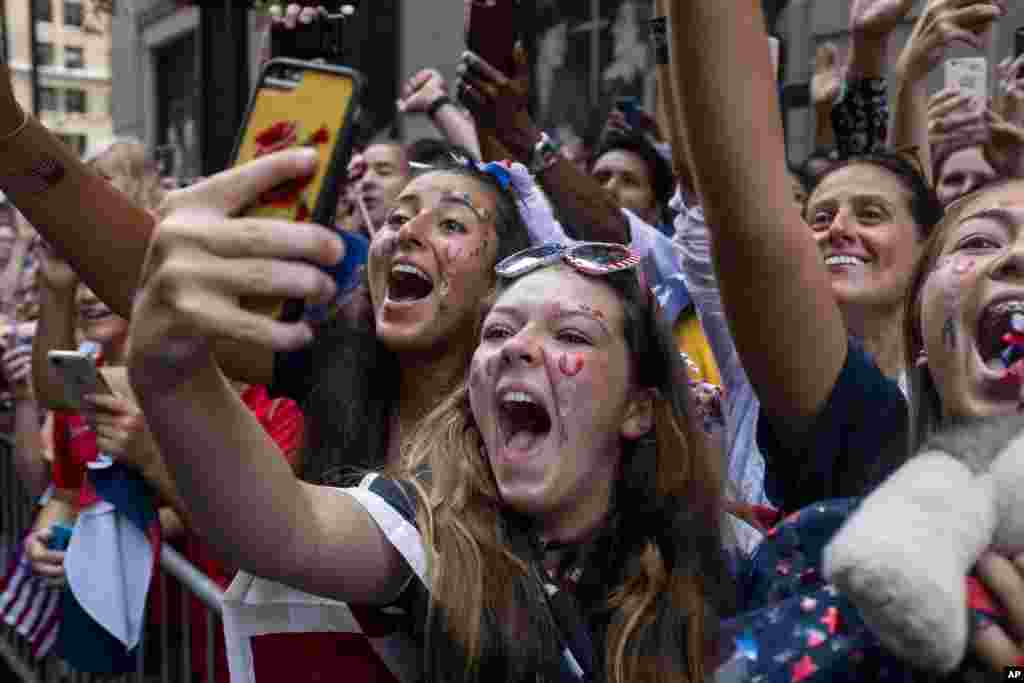 Fans celebrates as members of the the U.S. women&#39;s soccer team pass by during a ticker tape parade along the Canyon of Heroes in New York. The U.S. national team beat the Netherlands 2-0 to capture a record fourth Women&#39;s World Cup title.