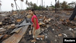A girl walks at the site of her house, which was burned during recent violence in Sittwe, June 16, 2012. 