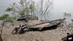 FILE - Villagers help a fisherman couple push their boat to the water at Satyanarayanpur village in the Sundarbans, India. 