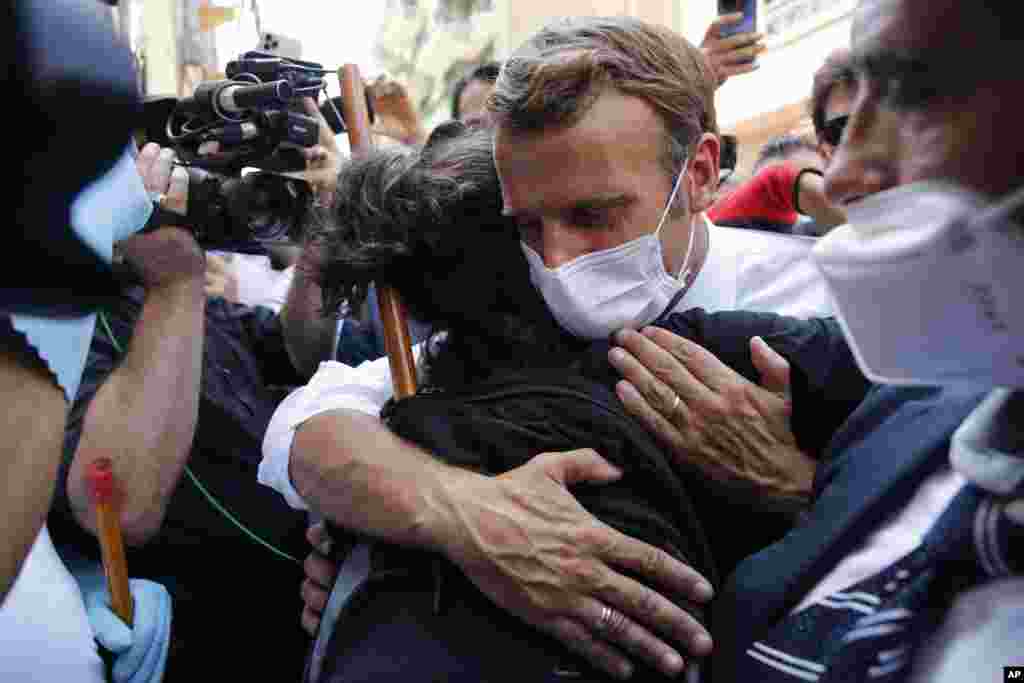 French President Emmanuel Macron hugs a person as he visits a badly damaged street in Beirut to offer French support to Lebanon after Tuesday&#39;s deadly port blast.