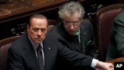 Italian Prime Minister Silvio Berlusconi, left, holds League North Party leader Umberto Bossi's hand during a finance vote at the parliament in Rome, November 8, 2011.