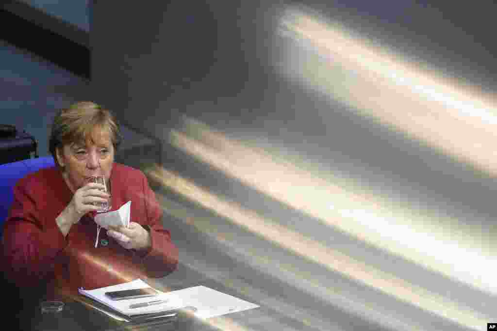 German Chancellor Angela Merkel drinks some water during a parliament session about a new law to battle the coronavirus pandemic at the Bundestag at the Reichstags building in Berlin, Germany.