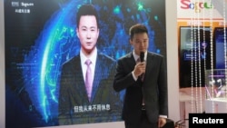 Xinhua news anchor Qiu Hao stands next to an AI virtual news anchor based on him, at a Sogou booth during an expo at the fifth World Internet Conference in Wuzhen town of Jiaxing, Zhejiang province, China, Nov. 7, 2018.