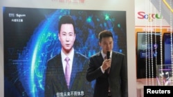 在中国乌镇国际互联网大会上，新华社新闻主播邱浩站在以他为原型的人工智能技术合成的新闻主播播放新闻的屏幕前(2018年11月7日)